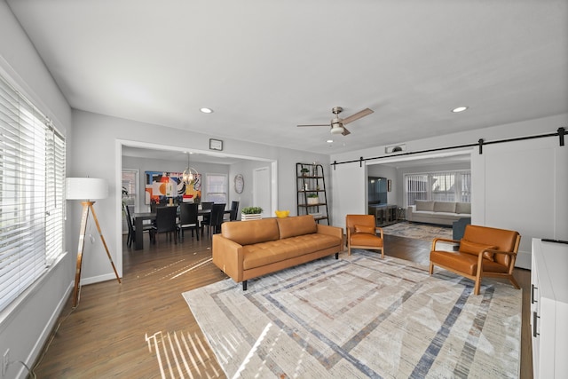 living room featuring light hardwood / wood-style flooring, a barn door, and ceiling fan