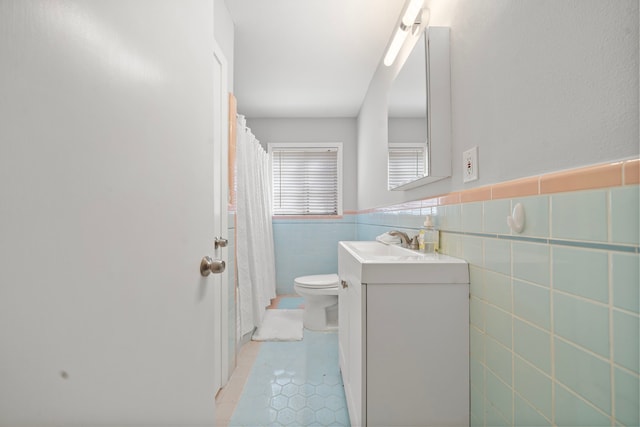 bathroom featuring tile walls, vanity, tile patterned floors, and toilet