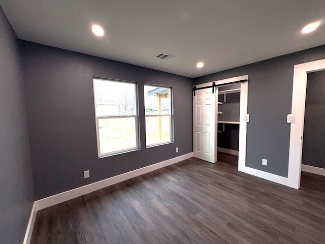 5053 E Fm 485, Cameron, TX 76520 - unfurnished bedroom with dark hardwood / wood-style flooring, a spacious closet, and a barn door