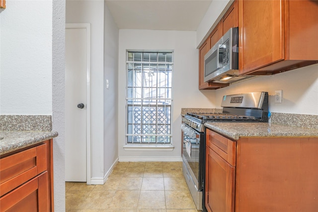 kitchen featuring light stone countertops, appliances with stainless steel finishes, and light tile patterned floors