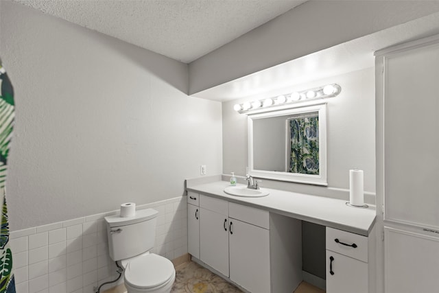 bathroom featuring vanity, tile walls, a textured ceiling, and toilet