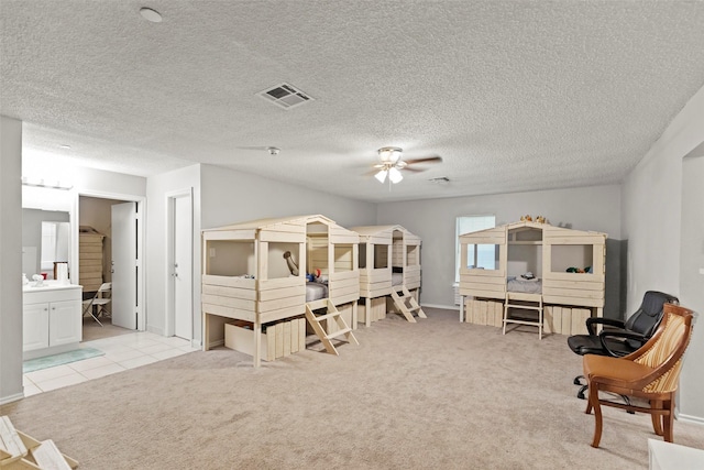 bedroom featuring connected bathroom, sink, light colored carpet, and a textured ceiling