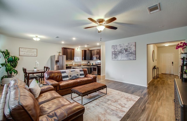 living room with ceiling fan and dark hardwood / wood-style flooring