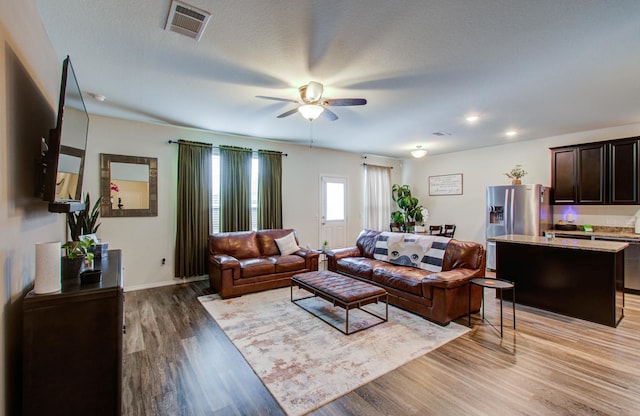 living room with ceiling fan, hardwood / wood-style floors, and a textured ceiling