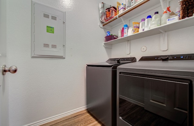 washroom featuring wood-type flooring, electric panel, and washing machine and dryer