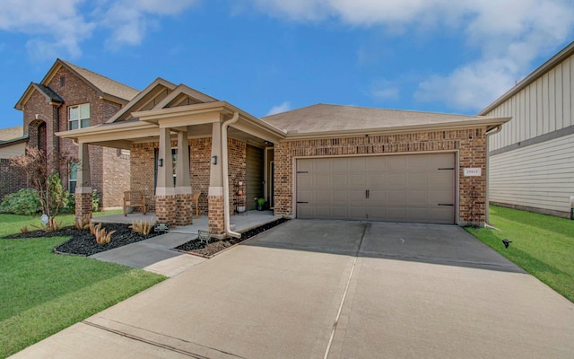 view of front of property featuring a garage, covered porch, and a front lawn