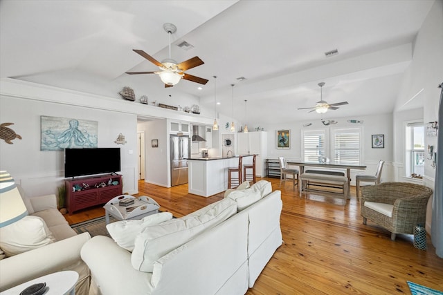 living room featuring ceiling fan, lofted ceiling, and light hardwood / wood-style flooring