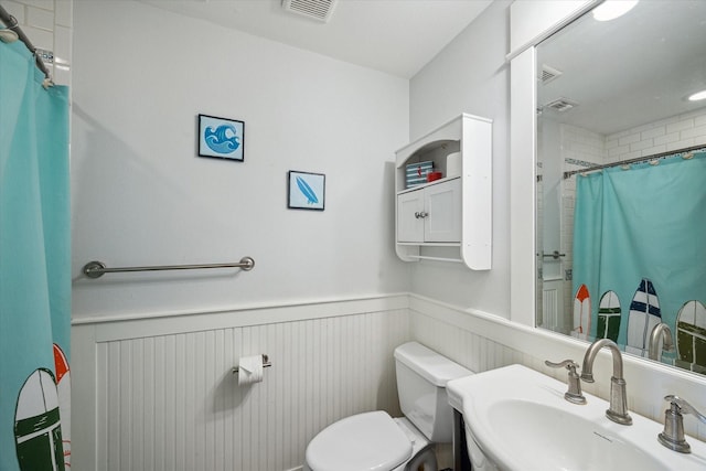 bathroom with a shower with shower curtain, toilet, and sink