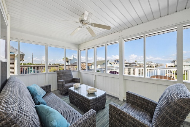 sunroom with a water view and ceiling fan