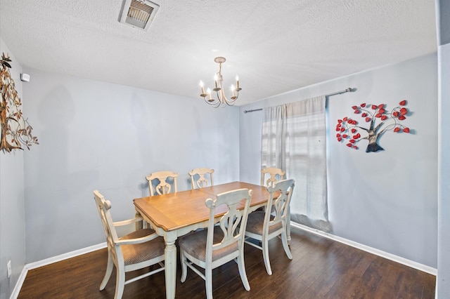 dining area with an inviting chandelier, a textured ceiling, and dark hardwood / wood-style flooring