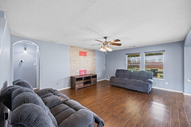 living room featuring ceiling fan, dark hardwood / wood-style floors, and a textured ceiling