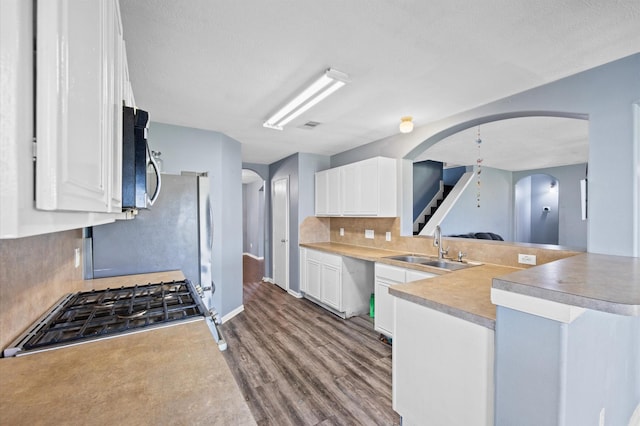 kitchen with white cabinetry, stainless steel appliances, kitchen peninsula, and sink