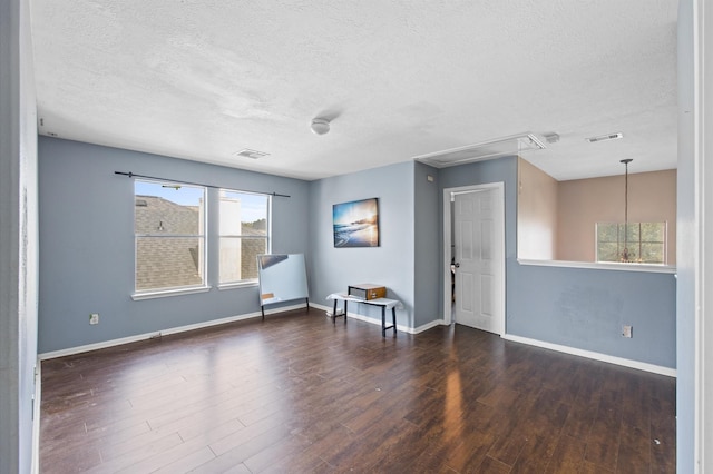 spare room with a textured ceiling and dark hardwood / wood-style flooring