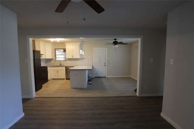 kitchen with sink, white cabinetry, black refrigerator, stainless steel dishwasher, and hardwood / wood-style floors