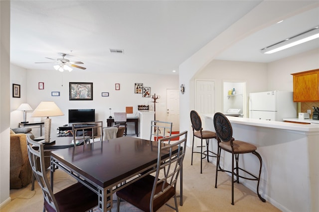 carpeted dining room with ceiling fan