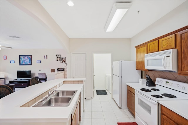 kitchen with light tile patterned flooring, sink, backsplash, a kitchen island with sink, and white appliances