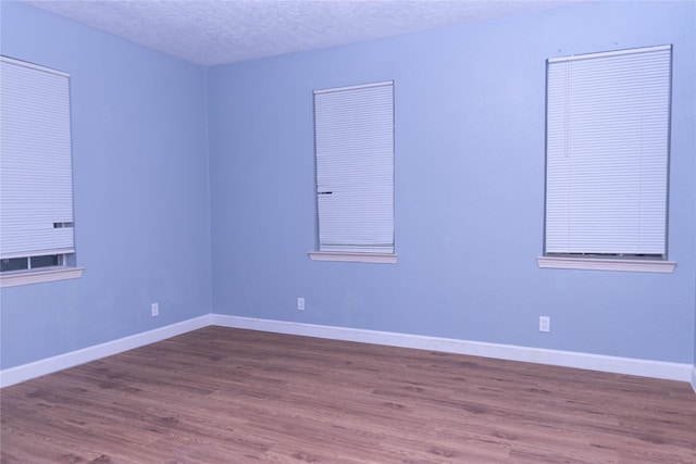 empty room with hardwood / wood-style flooring and a textured ceiling