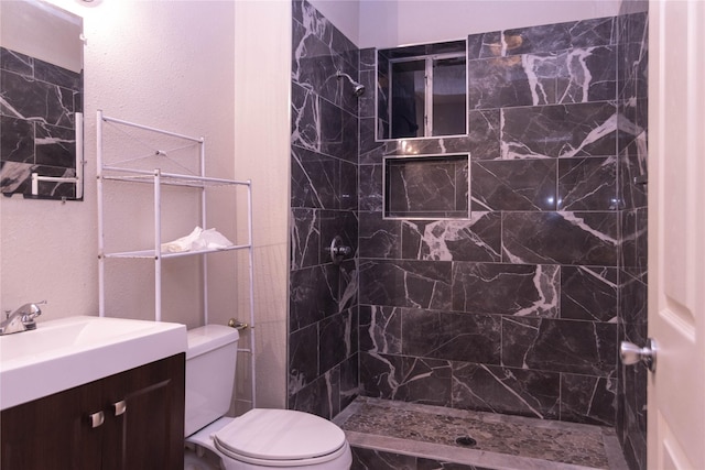 bathroom with vanity, a tile shower, and toilet