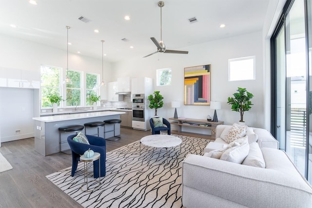 living room featuring ceiling fan, sink, and light hardwood / wood-style floors