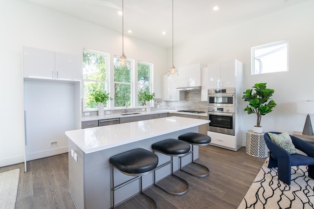 kitchen featuring stainless steel appliances, decorative light fixtures, a center island, and white cabinets