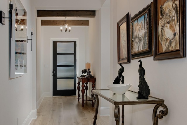 doorway with light wood-type flooring, an inviting chandelier, and beam ceiling