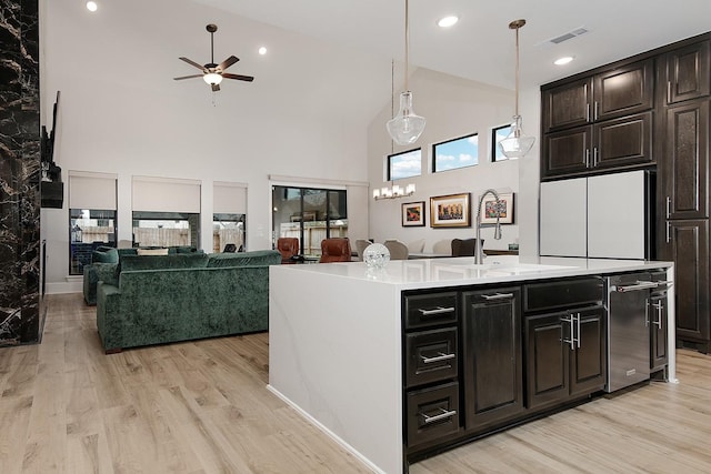 kitchen featuring sink, light hardwood / wood-style floors, hanging light fixtures, and a center island with sink