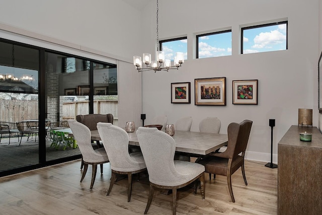 dining room featuring light hardwood / wood-style floors, a chandelier, and a high ceiling