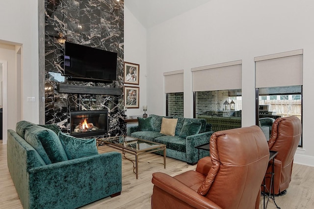 living room featuring hardwood / wood-style flooring, a premium fireplace, and high vaulted ceiling