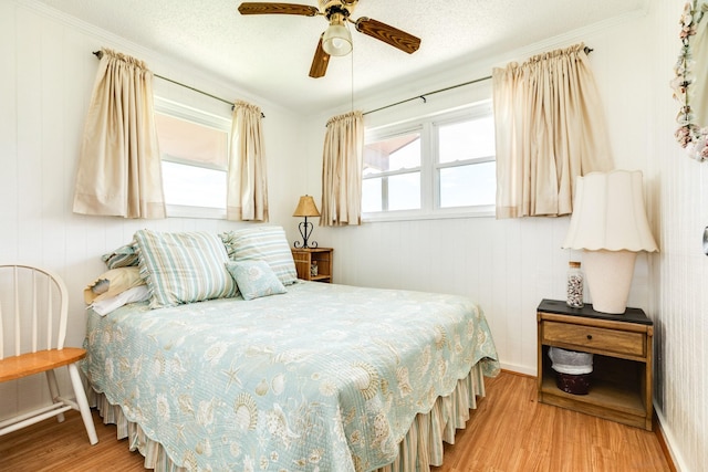 bedroom with multiple windows, light hardwood / wood-style flooring, and a textured ceiling