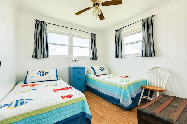 bedroom with light hardwood / wood-style flooring, ornamental molding, and ceiling fan