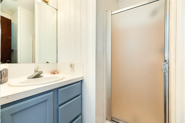 bathroom featuring a shower with door and vanity