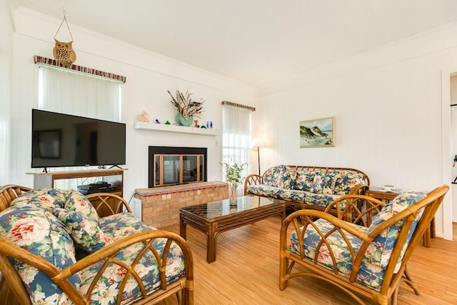 living room featuring wood-type flooring, a brick fireplace, and crown molding