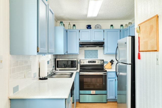 kitchen with sink, appliances with stainless steel finishes, a textured ceiling, blue cabinets, and decorative backsplash