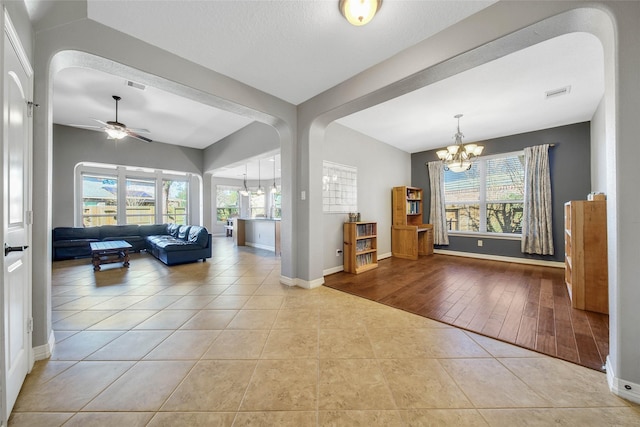 living room featuring light tile patterned flooring and ceiling fan with notable chandelier