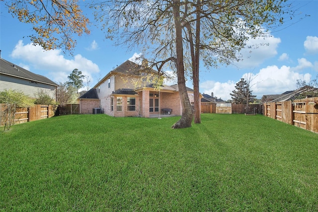 rear view of house featuring central AC unit and a lawn