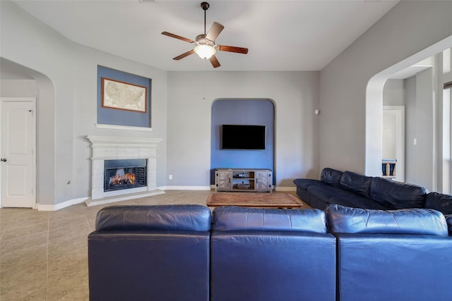 living room with light tile patterned floors, a tile fireplace, and ceiling fan