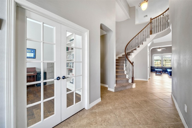 tiled entryway featuring french doors and a towering ceiling