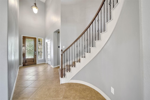 entryway with a towering ceiling and light tile patterned floors