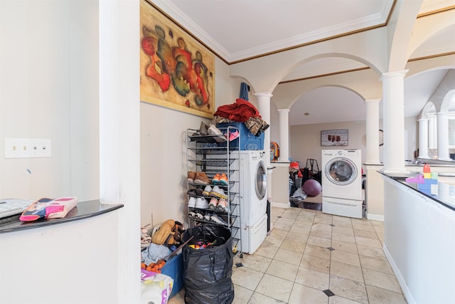 clothes washing area featuring decorative columns, ornamental molding, light tile patterned floors, and washer and clothes dryer