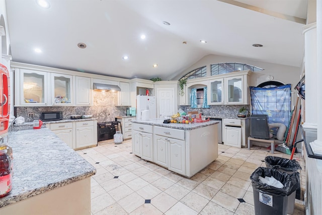 kitchen with white cabinetry, backsplash, vaulted ceiling, and wall chimney exhaust hood