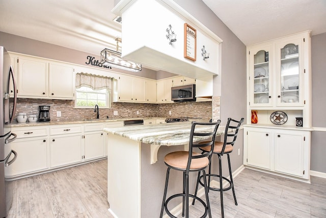 kitchen featuring a center island, a sink, light stone countertops, stainless steel appliances, and backsplash