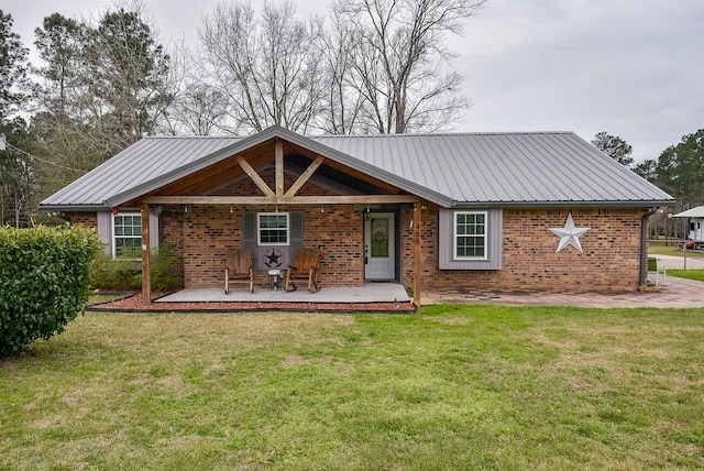 rear view of property with metal roof, brick siding, and a yard