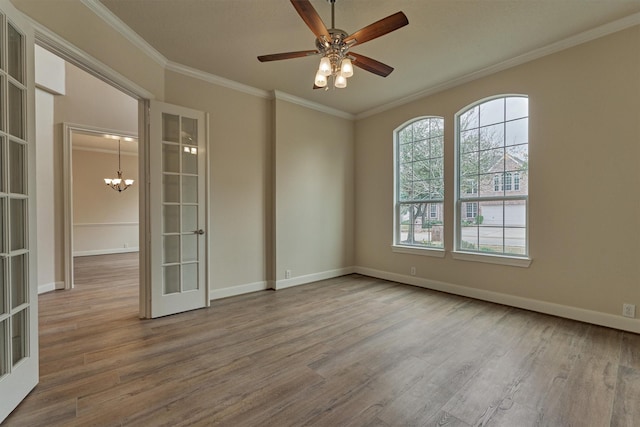 unfurnished room with hardwood / wood-style floors, crown molding, ceiling fan with notable chandelier, and french doors