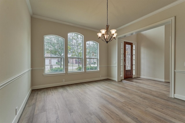 unfurnished room with an inviting chandelier, ornamental molding, and light wood-type flooring