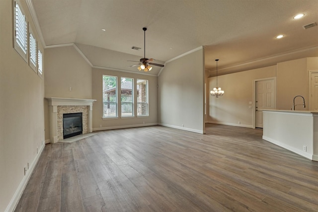 unfurnished living room with vaulted ceiling, ornamental molding, ceiling fan with notable chandelier, and hardwood / wood-style floors