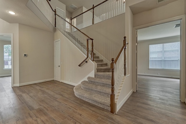 stairway featuring wood-type flooring and a towering ceiling