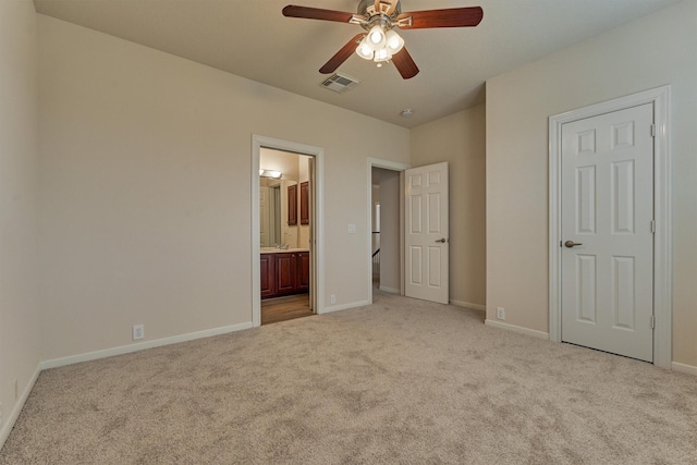 unfurnished bedroom featuring connected bathroom, light colored carpet, and ceiling fan