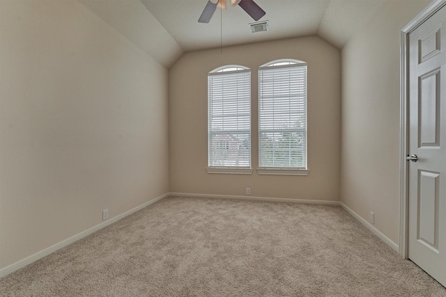 empty room featuring vaulted ceiling, plenty of natural light, light colored carpet, and ceiling fan