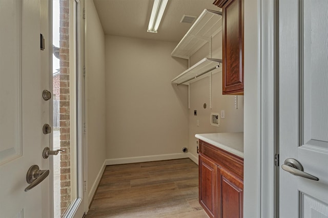 laundry area featuring hookup for a washing machine, cabinets, and light hardwood / wood-style flooring