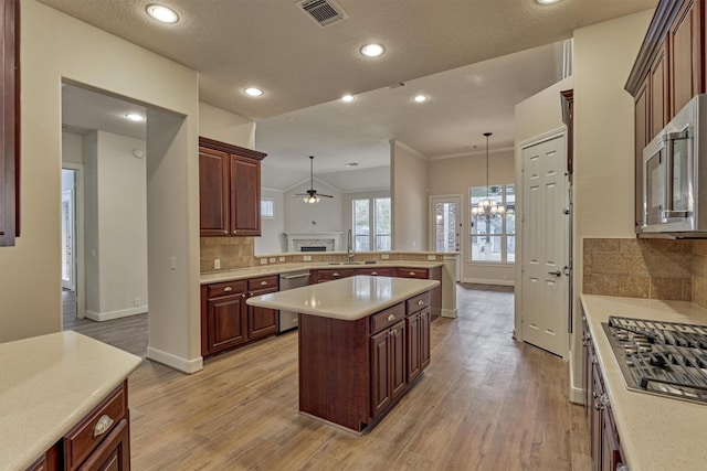 kitchen with pendant lighting, a kitchen island, light hardwood / wood-style floors, and appliances with stainless steel finishes